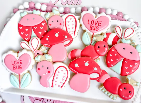 Sugar cookies in the shape of flowers mushrooms caterpillars decorated in pink and red icing